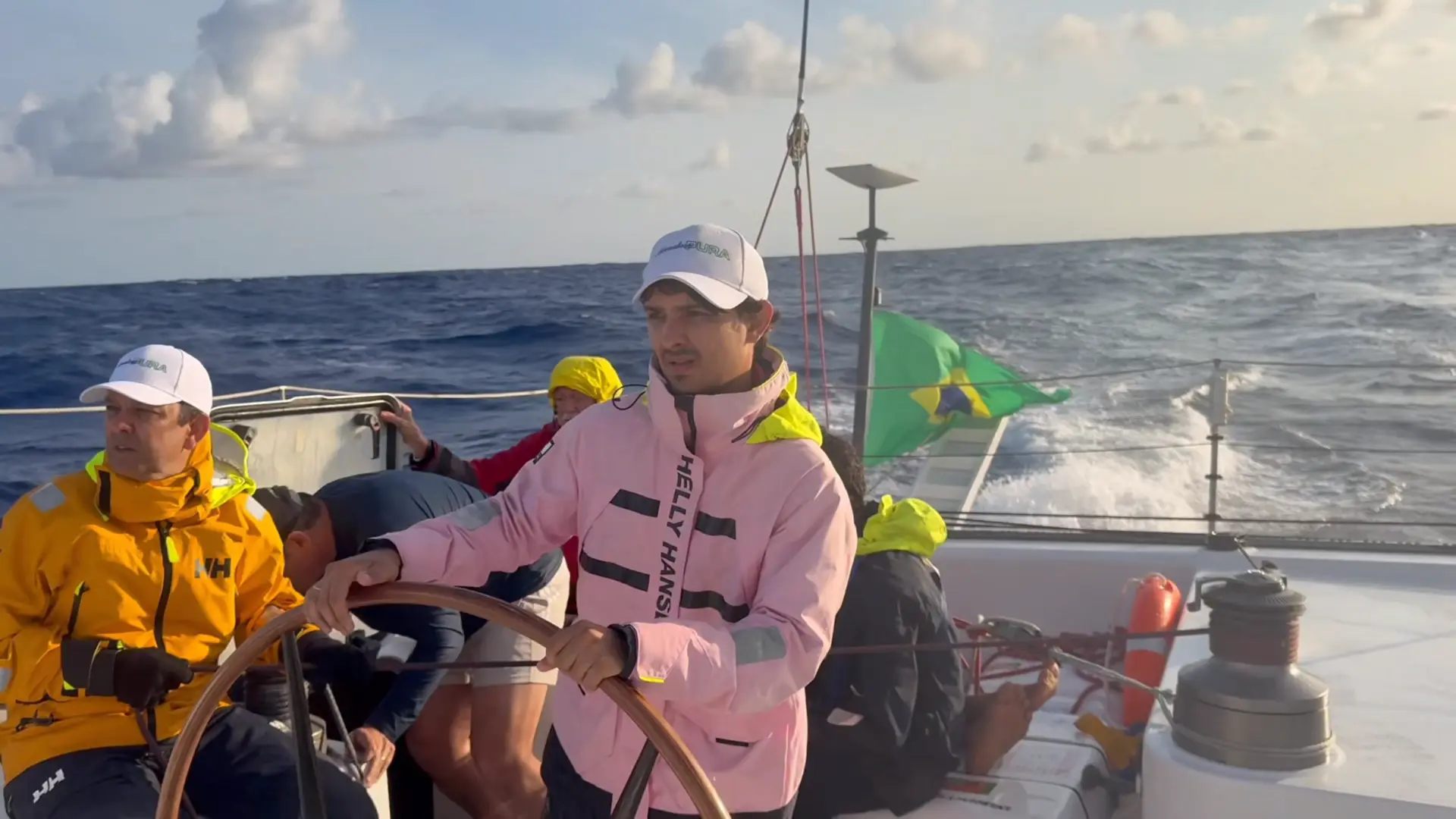Timoneiro ao leme com dois tripulantes durante o turno em mar aberto