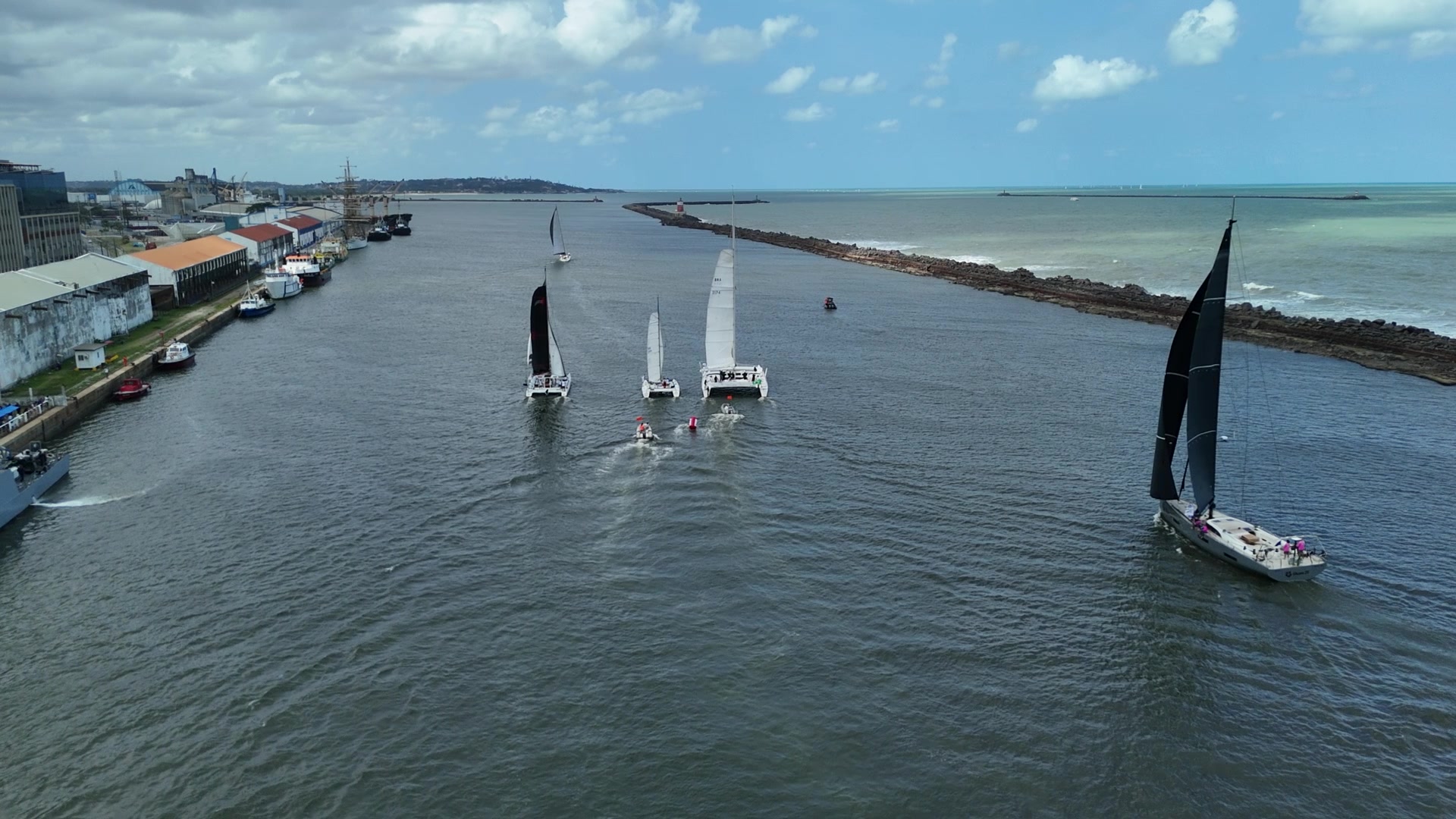 Proa de veleiro deixando a barra do porto do Recife com a cidade encolhendo ao fundo
